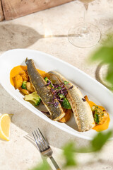 Seabass Fillet with Vegetables and Carrot Sauce in Sunlit Still Life Setting