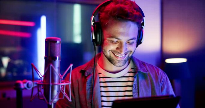 Man, musician and headphones with tablet in recording studio for music production, audio streaming and face in neon. Artist, happy and media industry with digital app for song lyrics and learning
