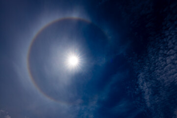 A captivating image of a sun halo against a deep blue sky, created by the refraction of sunlight...