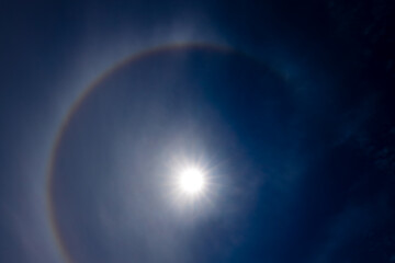A captivating image of a sun halo against a deep blue sky, created by the refraction of sunlight...
