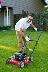 Gardening details. Garden worker starting the lawnmower and cutting grass in garden