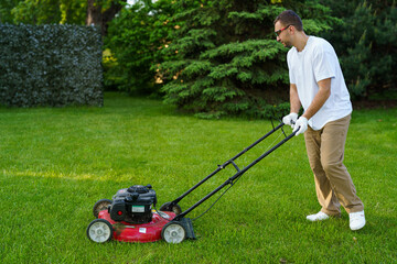 Gardener mowing the lawn. Landscape design. Green grass background