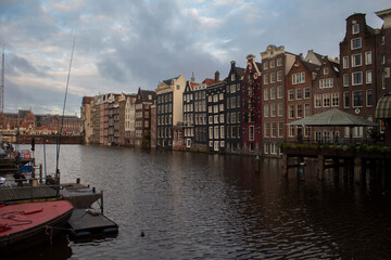 Dutch-style houses along a canal in Amsterdam, with boats and the sky.