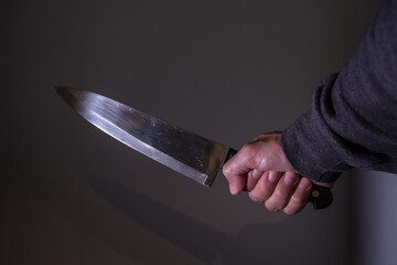 Großes Küchenmesser in geballter Faust / Hand von Mann 