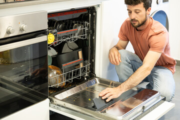 young man putting a dishwasher in his house after a meal. Man doing housework.