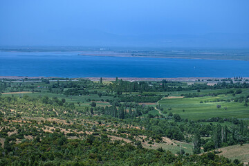 Wide field landscape photo. Looking down from the hill. Sparse trees, grass and lakeunder the clear sky. Konya, Turkey.