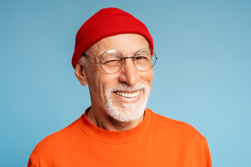 Caucasian gray haired bearded handsome senior man in glasses winking looking at camera