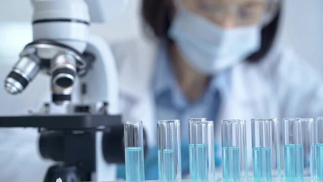 Test tubes with a blurred scientist in a lab coat in the background