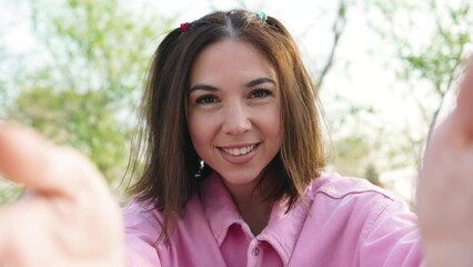 Happy brunette woman blogger sets up video camera for making video blog on sunset outdoors pov