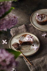 Fresh homemade chocolate muffin close up on a rustic plate with lilac flowers