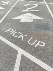 "PICK UP" text on aspfalt on pickup area on parking with numbers and arrows markings, indicating a designated zone for vehicle curbside orders at the local store. © elena.tres