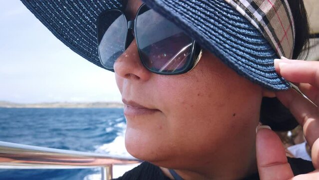 Middle agged woman with sunglasses and hat enjoing boat ride. High quality 4k footage
