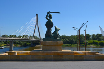 Warsaw, Poland. Statue of Mermaid (Polish: Warszawska Syrenka) symbol of Warsaw by the Vistula river on the background of Swietokrzyski Bridge. Spring time in Warsaw, Poland © PaulSat