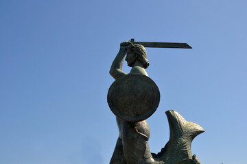 Statue of Mermaid (Polish: Warszawska Syrenka) symbol of Warsaw by the Vistula river. Closeup view with blue sky background © PaulSat