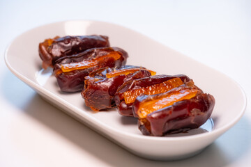 a white porcelain platter with magnificent large fresh Dubai dates filled with candied orange
