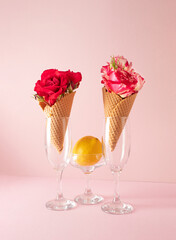 Ice cream cone with colorful flowers and lemon on pastel pink background. Minimal summer concept.