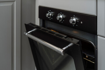 Electric oven with open door and control panel with knob at kitchen