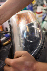 showing hands effectively repairing a car headlight in a workshop environment