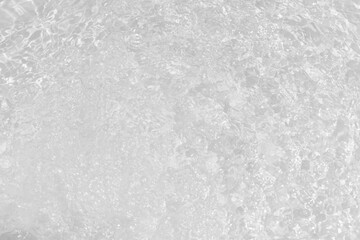 White water with ripples on the surface. Defocus blurred transparent white colored clear calm water surface texture with splashes and bubbles. Water waves with shining pattern texture background.