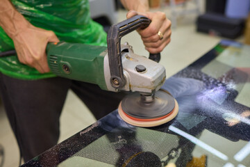 A professional technician expertly polishes glass surfaces in a workshop with precision