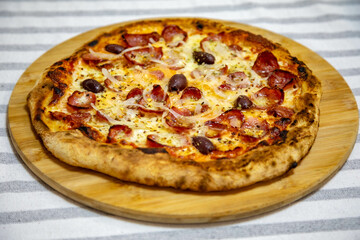 Calabrian sausage pizza served on a round board and set table