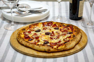 Calabrian sausage pizza served on a round board and set table