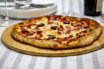 Calabrian sausage pizza served on a round board and set table