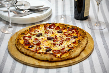 Calabrian sausage pizza served on a round board and set table