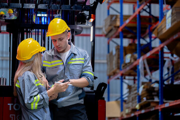 Two male and female factory checkers are discussing work on a warehouse truck. While working in a warehouse for industrial products