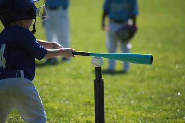 Child hitting a baseball on a tee with a bat, tball game