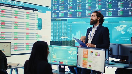 Chief executive officer reviews data shown on big display in the office, screens with infographics, finance analysis and organizational progress. Telecommunications system control room. Camera B.
