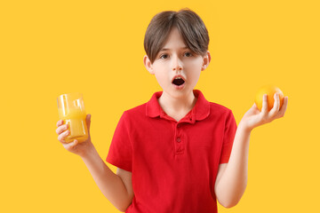 Shocked little boy with orange and glass of juice on color background