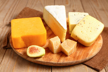 Board with tasty cheese on wooden background