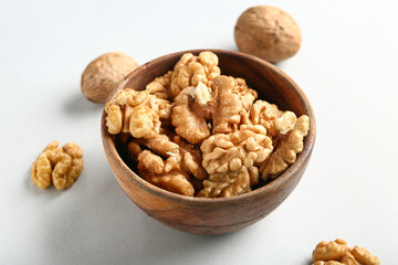 Bowl of tasty walnuts on white background