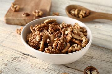 Bowl of tasty walnuts on white wooden background