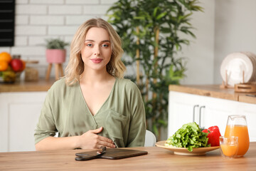 Young pregnant woman at table in kitchen