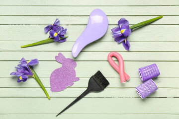 Paper Easter bunny with hairdressing accessories and flowers on green wooden background