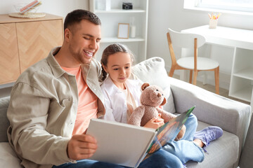 Obraz premium Father reading fairy tale to his daughter at home