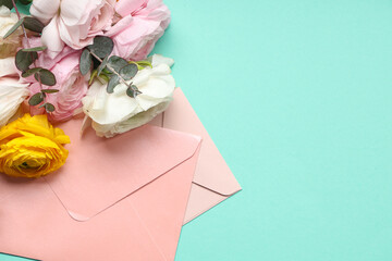 Beautiful ranunculus flowers with eucalyptus and envelopes on turquoise background