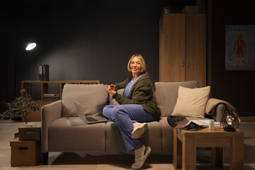 Female nurse with notebook and laptop studying on sofa at hospital in evening