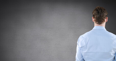 Image of rear view of caucasian man touching invisible screen on grey background with copy space