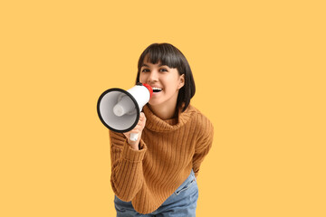 Young woman with megaphone  on yellow background