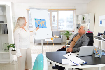 Obraz premium Mature business people with cocktail and world map ready for summer vacation in office