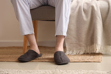 Man in slippers sitting on soft bench with plaid - Powered by Adobe