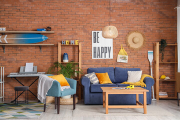 Interior of modern room with surfboard and sofa near brick wall