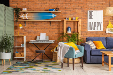 Interior of modern room with surfboard and sofa near brick wall