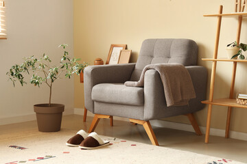 Pair of soft slippers on carpet near armchair in modern living room
