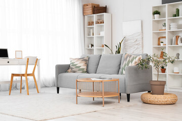 Interior of living room with cozy grey sofa and wooden coffee table