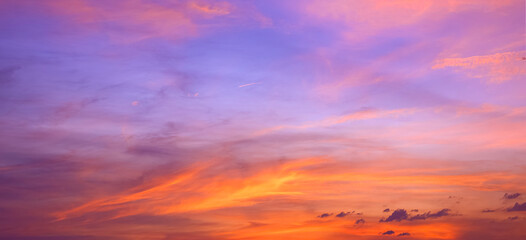 Dusk sky background after sundown with colorful orange sunlight clouds on blue evening sky, panoramic view