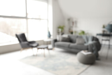 Stylish interior of white living room with sofa and armchair, blurred view